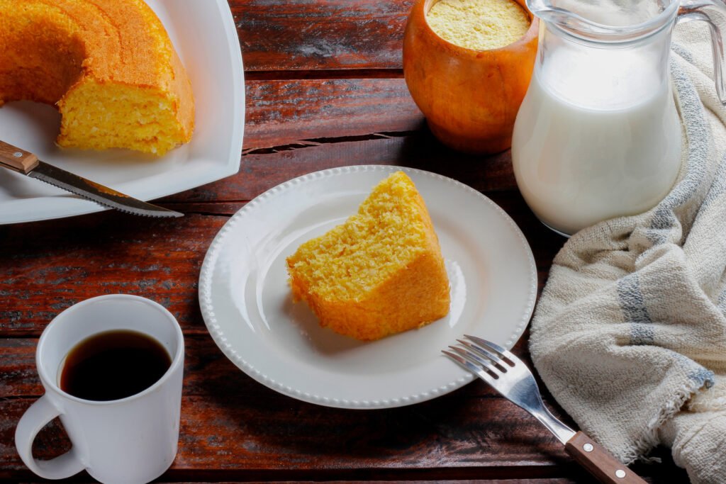 Fatia de bolo de milho servida com café e leite