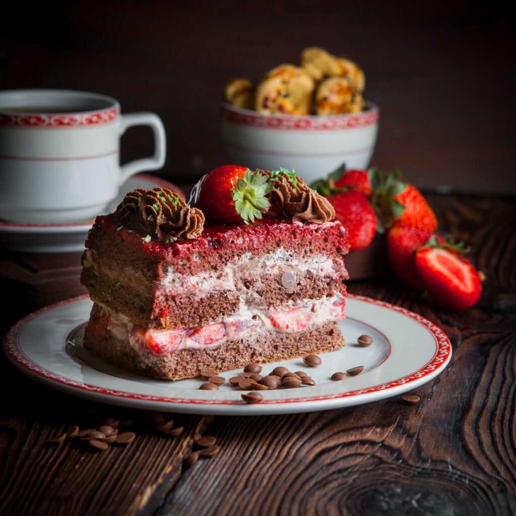 Fatia de bolo de chocolate com recheio de morango e decoração de chantilly e morangos