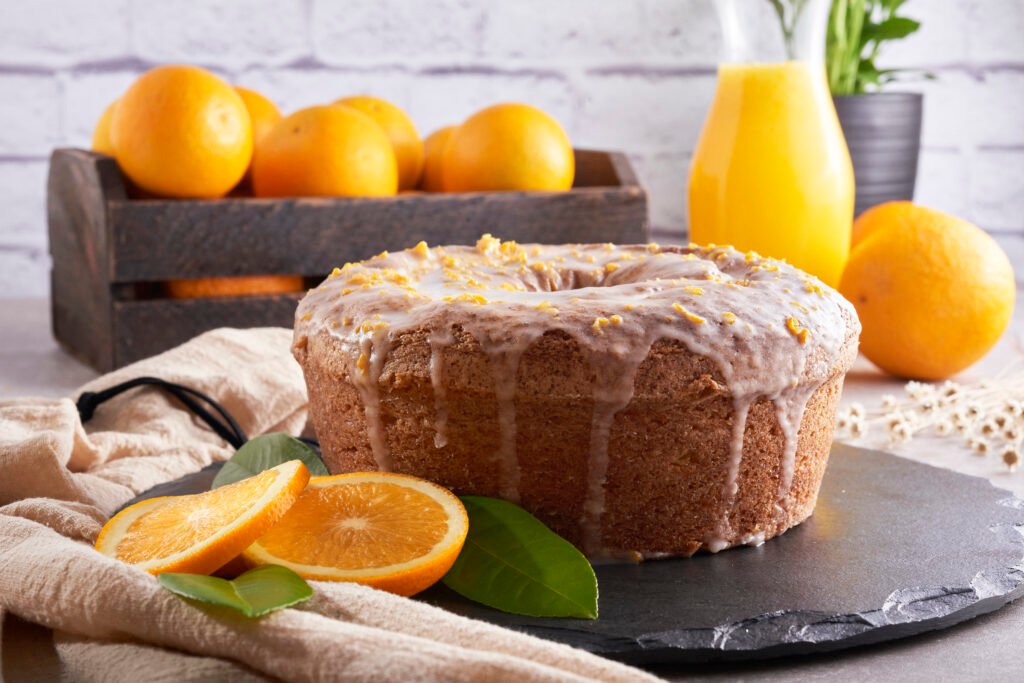 Bolo de laranja com cobertura de açúcar e suco de laranja, decorado com fatias de laranja