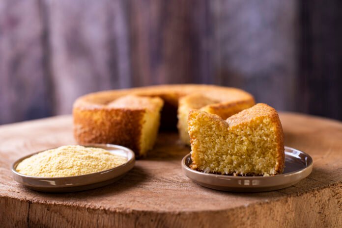 Fatia de bolo de fubá fofinho com um prato de fubá ao lado.