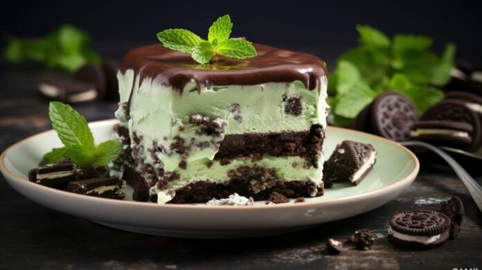 Bolo gelado de chocolate com menta, decorado com folhas de hortelã e pedaços de biscoito recheado