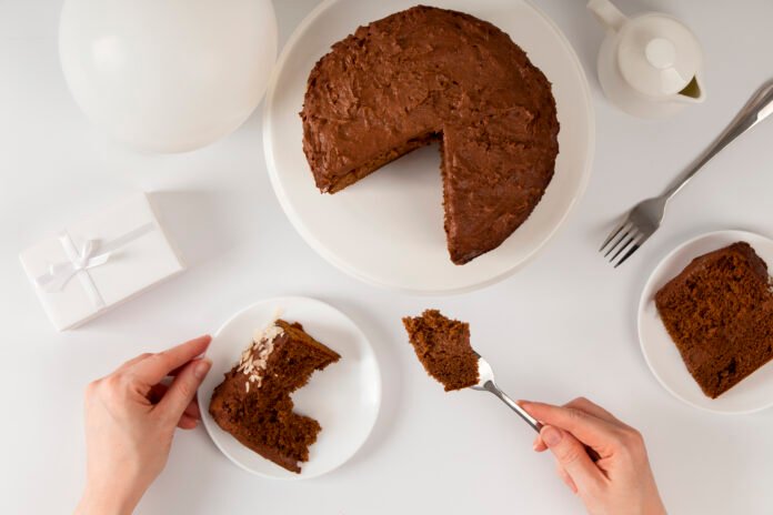 Bolo de chocolate sem açúcar servido em prato branco com fatias individuais e decoração minimalista.