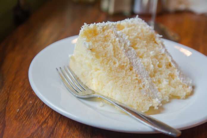 Fatia de bolo de leite ninho com textura macia e cobertura cremosa em um prato branco.