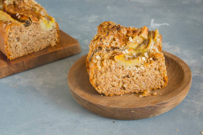 Fatia de bolo de maçã vegano com nozes em prato de madeira