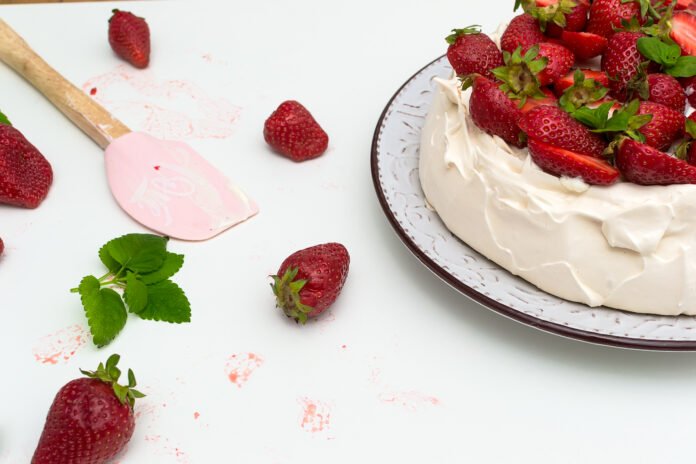 Bolo de morango com chantilly decorado com morangos frescos e folhas de hortelã.