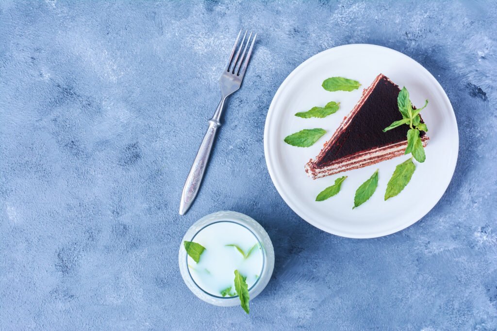 Fatia de bolo gelado de chocolate com menta decorada com folhas de hortelã em um prato branco