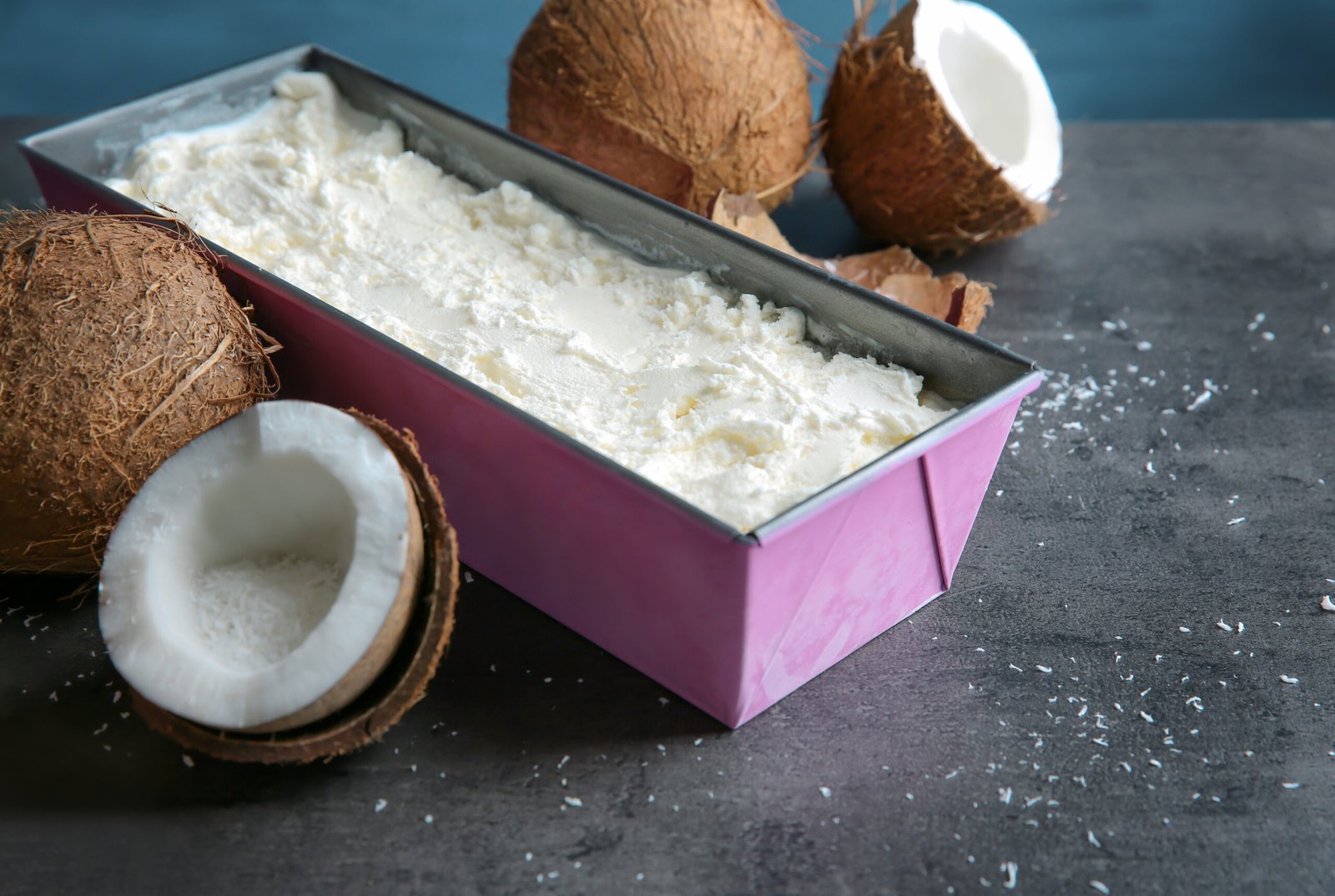 Forma com bolo gelado de coco e leite condensado, decorado com pedaços de coco ao lado.