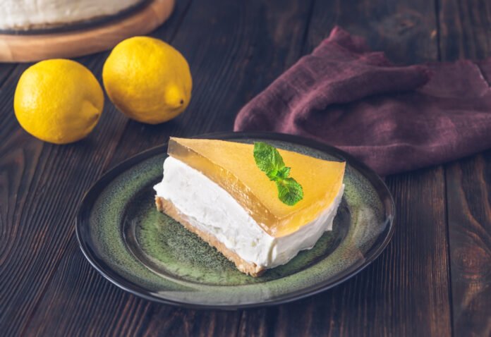 Fatia de bolo gelado de limão siciliano com creme de leite condensado decorada com folha de hortelã.