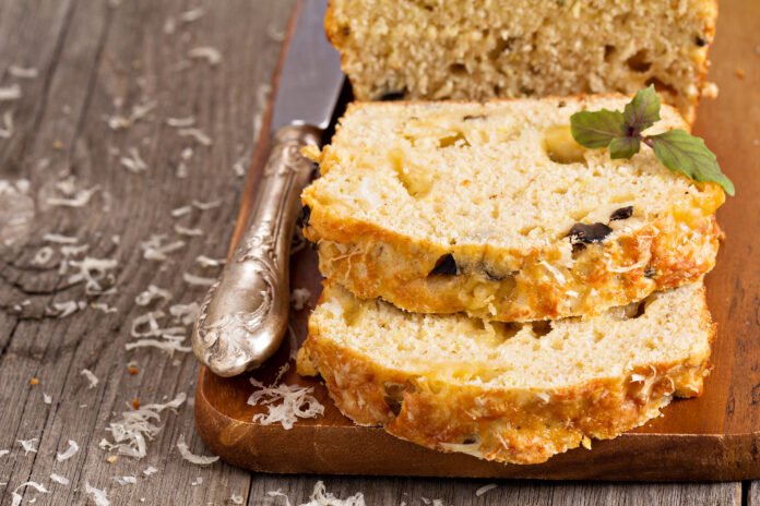 Fatias de bolo de abacaxi com linhaça sobre uma tábua de madeira, decoradas com folhas frescas.