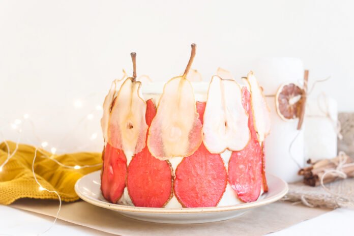 Bolo de frutas tropicais decorado com fatias de frutas desidratadas e cobertura de marshmallow.