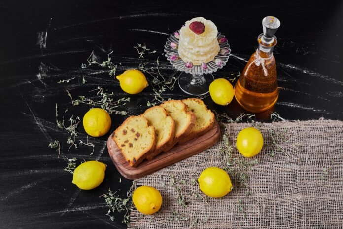 Bolo de limão caseiro com sementes de papoula decorado com limões frescos e um toque especial de calda cítrica.