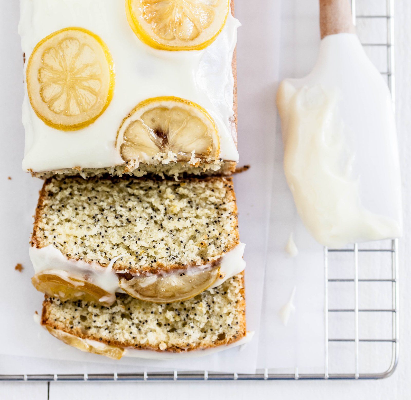 Bolo de limão siciliano com sementes de chia decorado com fatias de limão e cobertura branca.