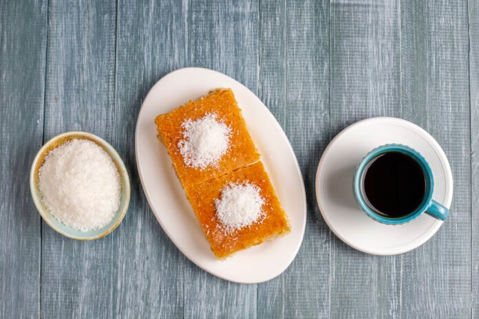 Fatias de bolo de milho caseiro com coco ralado, servidas com uma xícara de café.