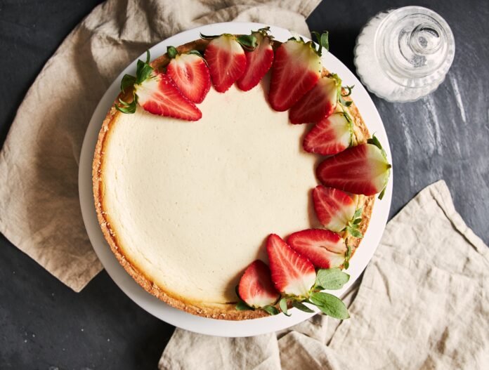 Bolo de iogurte com morango decorado com fatias de morango fresco sobre um prato branco.